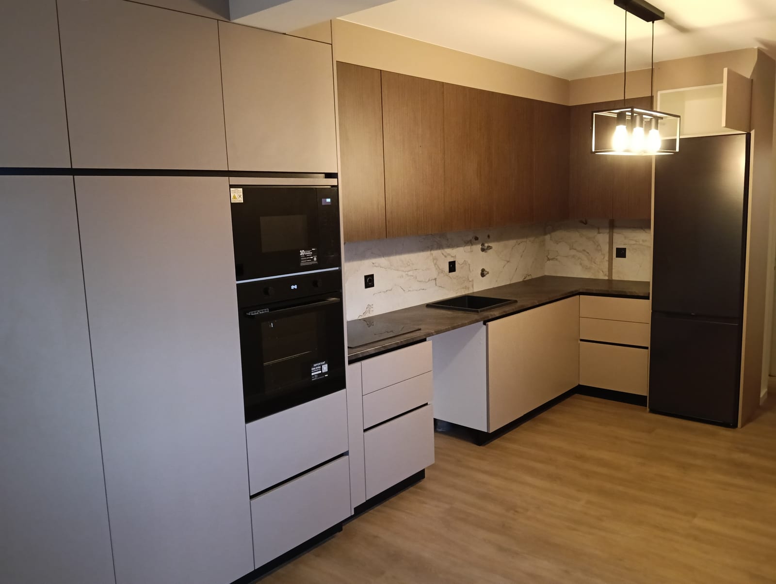 Cozinha em carvalho e bege, com painel em mármore e fornos encastrados