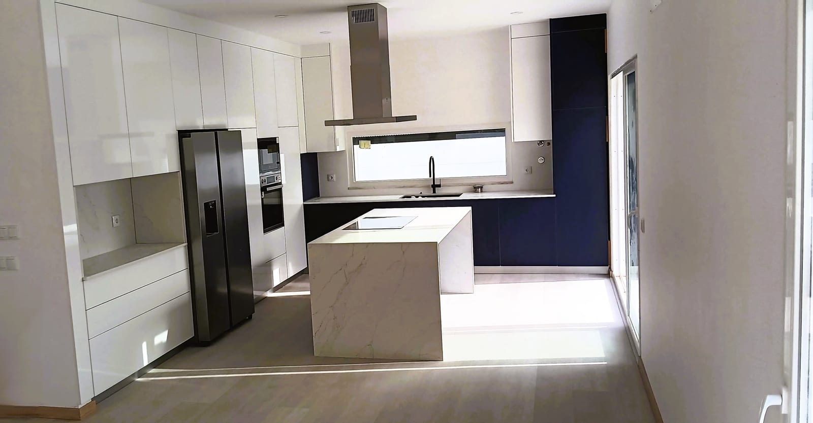 Kitchen with a stone island, navy units and a ceiling extractor