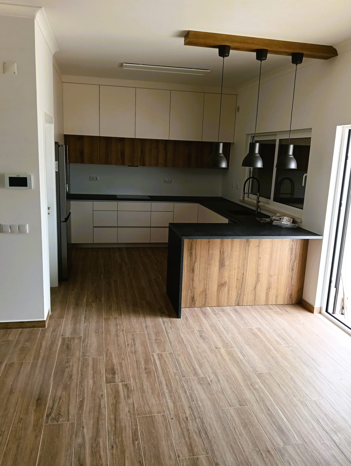 Cozinha com península em madeira, tampo escuro e três suspensões